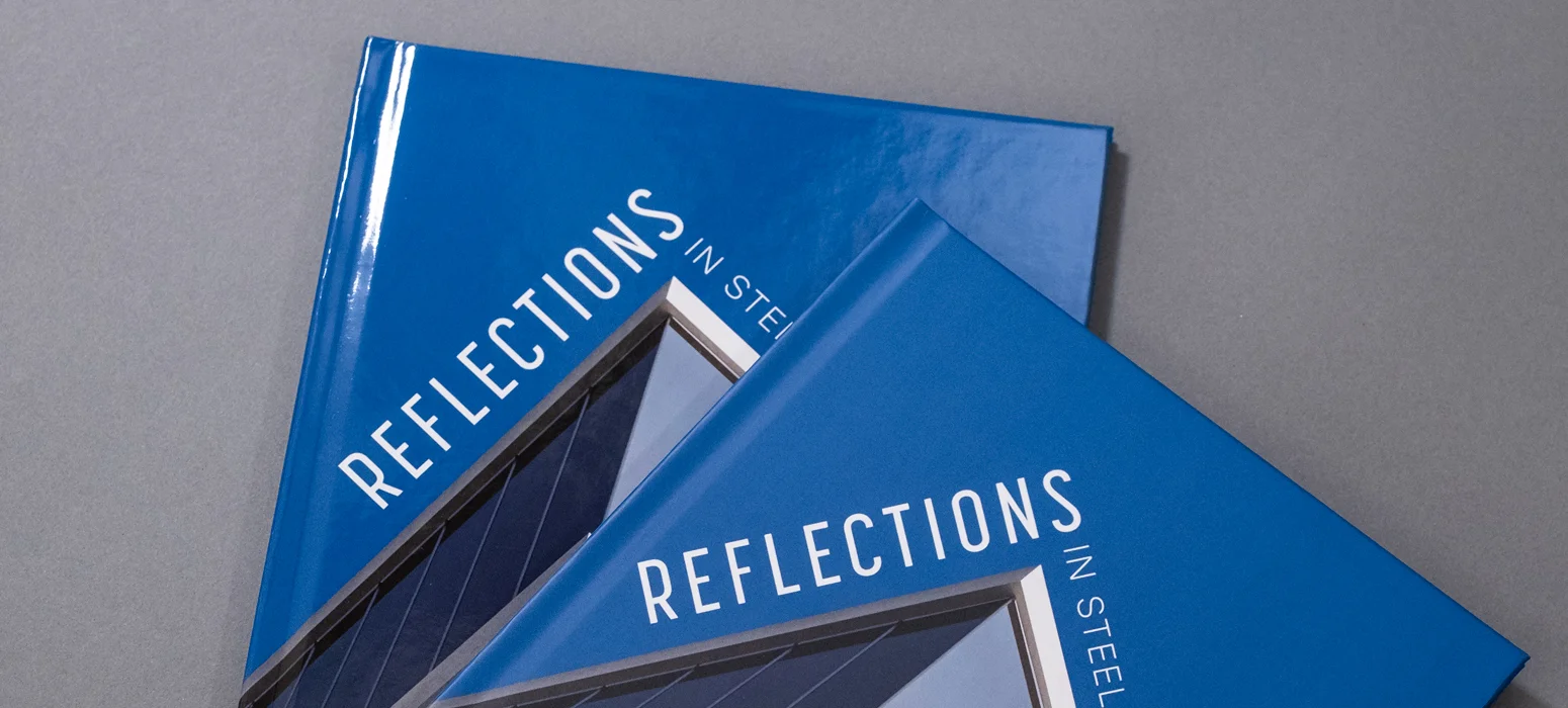 Deux exemplaires d'un livre en couverture rigide imprimée intitulé « Reflections » montrant une couverture bleue brillante.